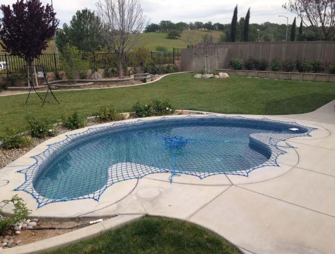 Backyard swimming pool under construction with blue tile liner and surrounding patio