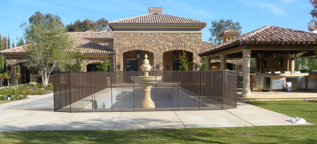Mediterranean-style stone house with a gated front walkway and tiled roof under a clear sky