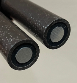 Two black speckled cylindrical rods with silver ends on a light background