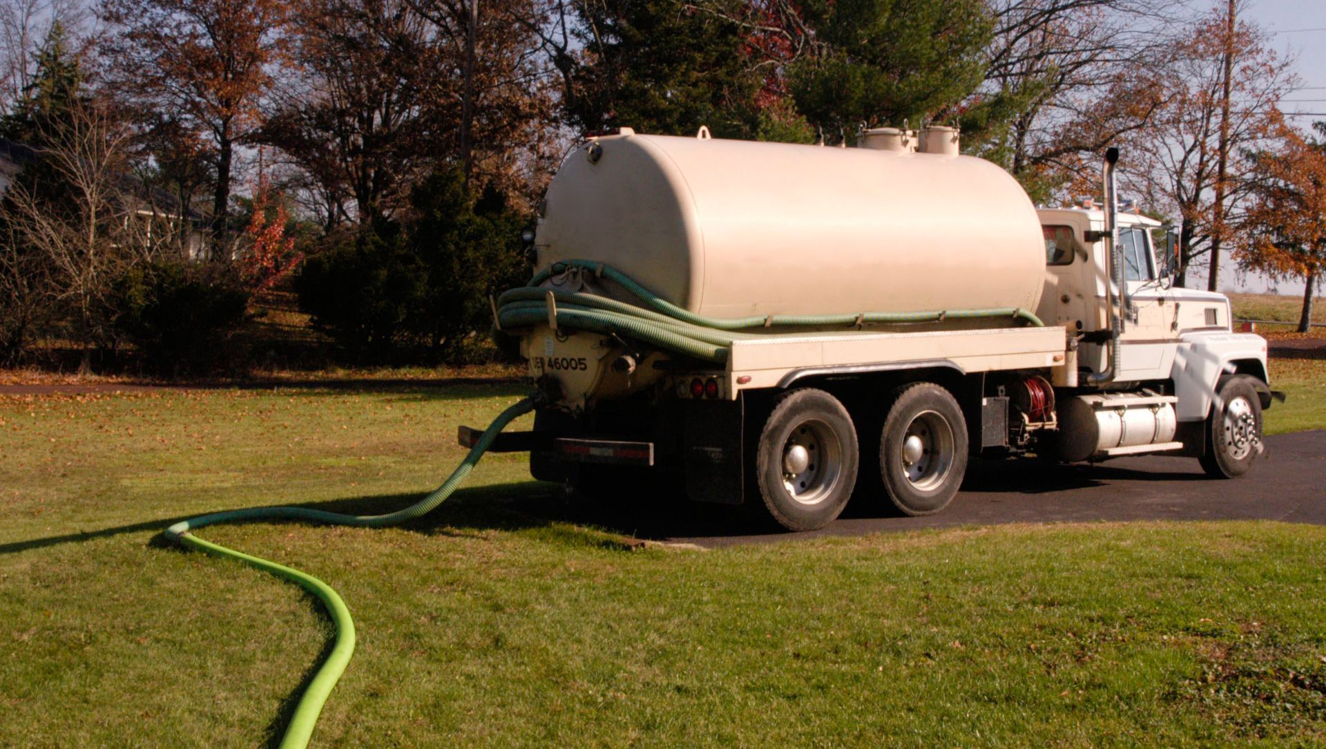 Septic tank installation in progress; concrete container partially buried in sandy soil, orange pipe attached.