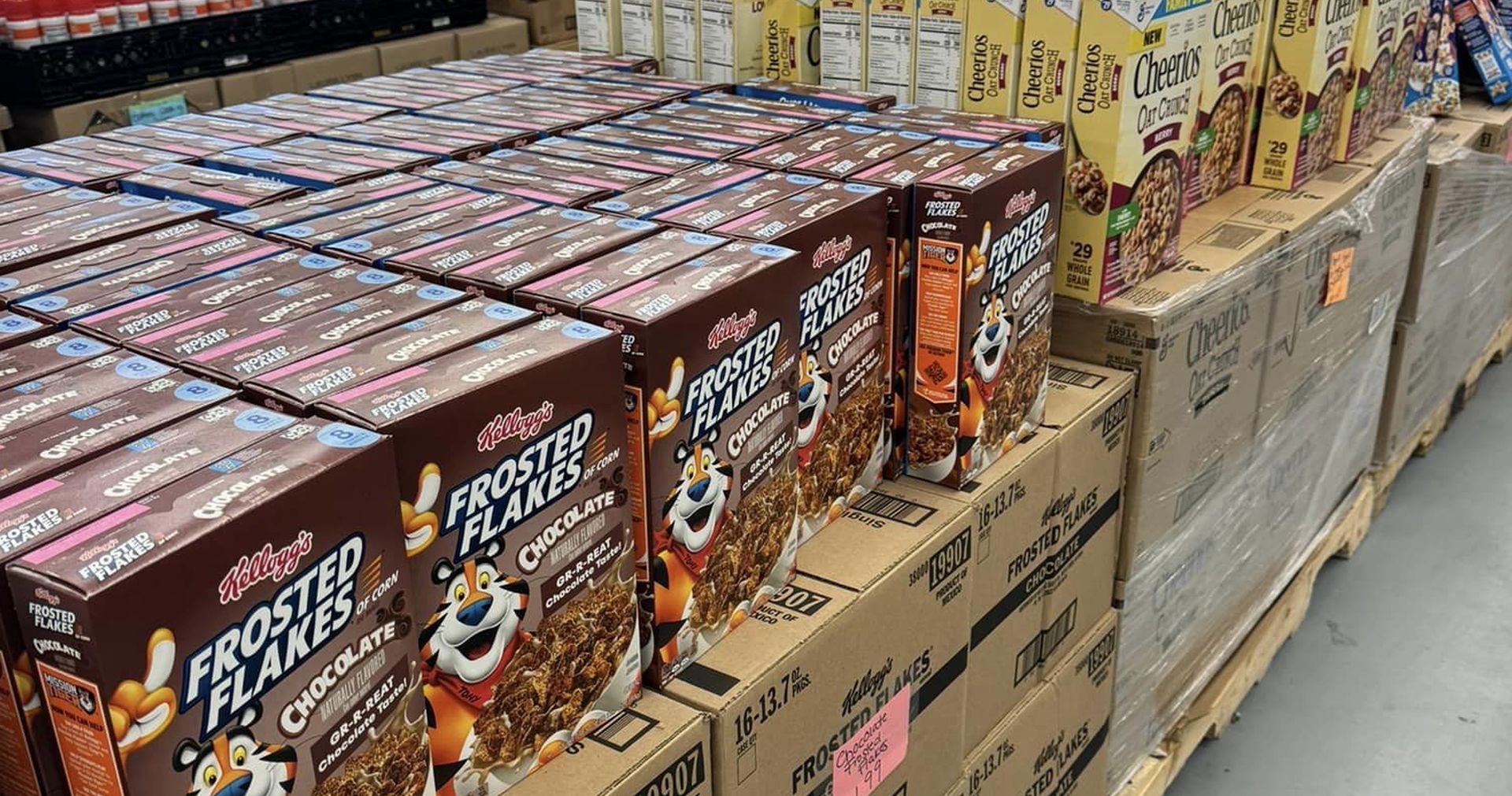 Boxes of frosted flakes cereal are lined up on a shelf in a store.