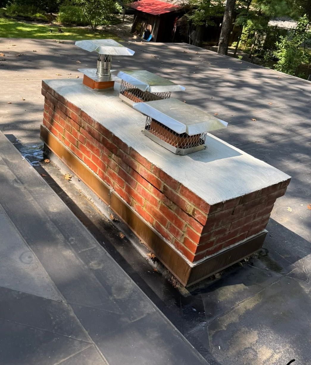 Brick rooftop vent on a concrete platform in a sunlit outdoor area, with trees in the background