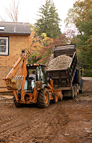 A tractor and truck is  beside the house.