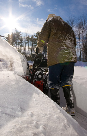 Worker removing snow with machine.