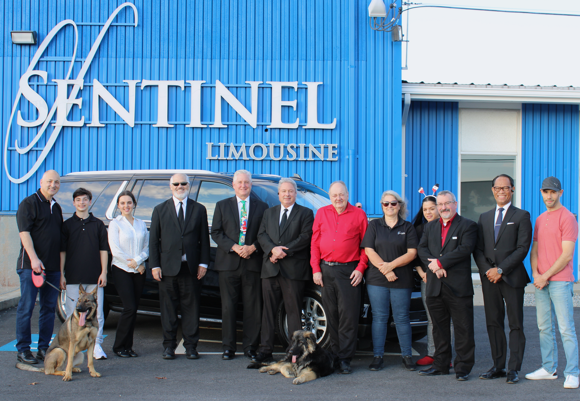 Group of people and two dogs in front of a business with 