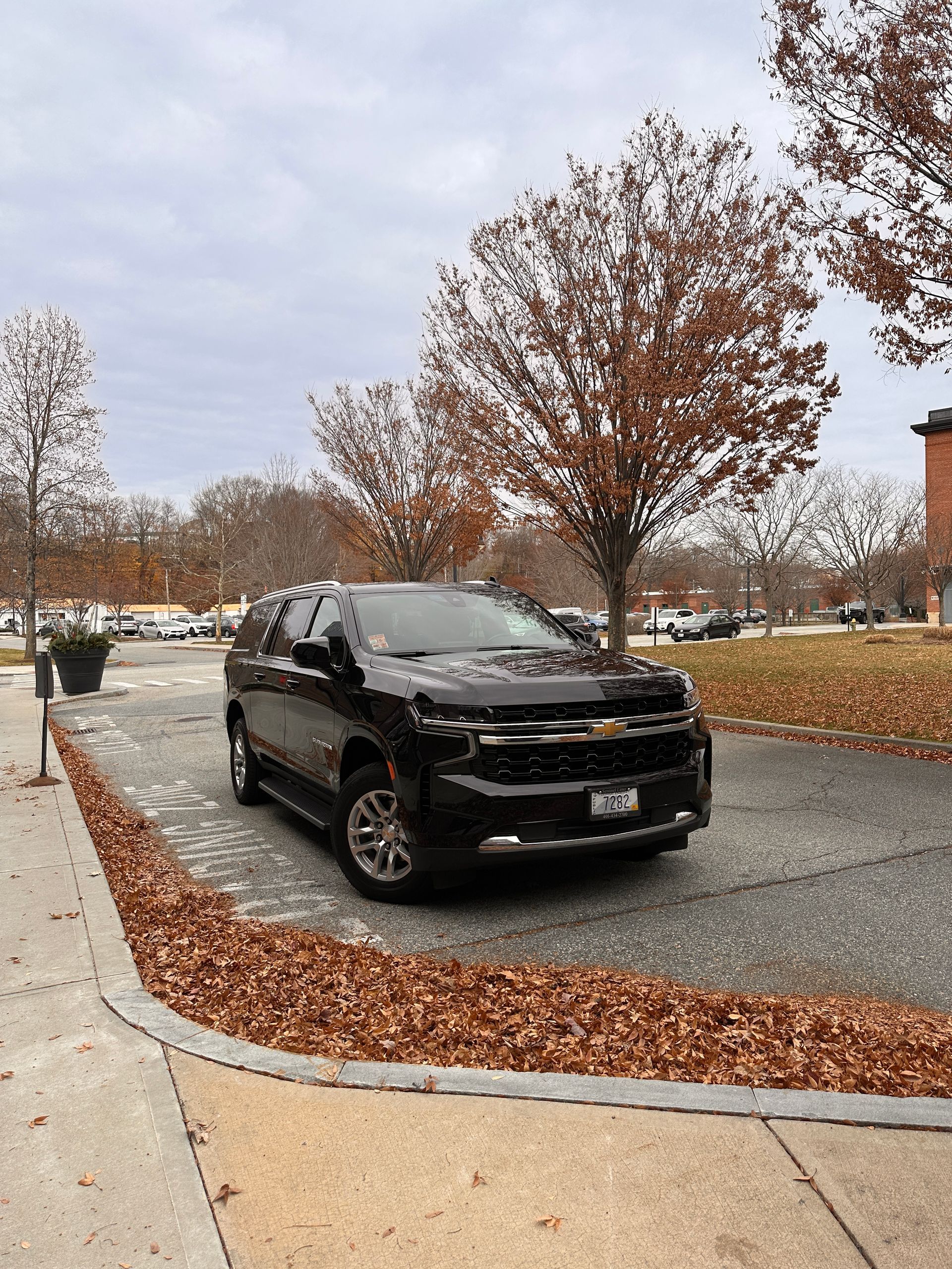 Black Sentinel Limousine SUV parked on a tree-lined street during the fall in Rhode Island.
