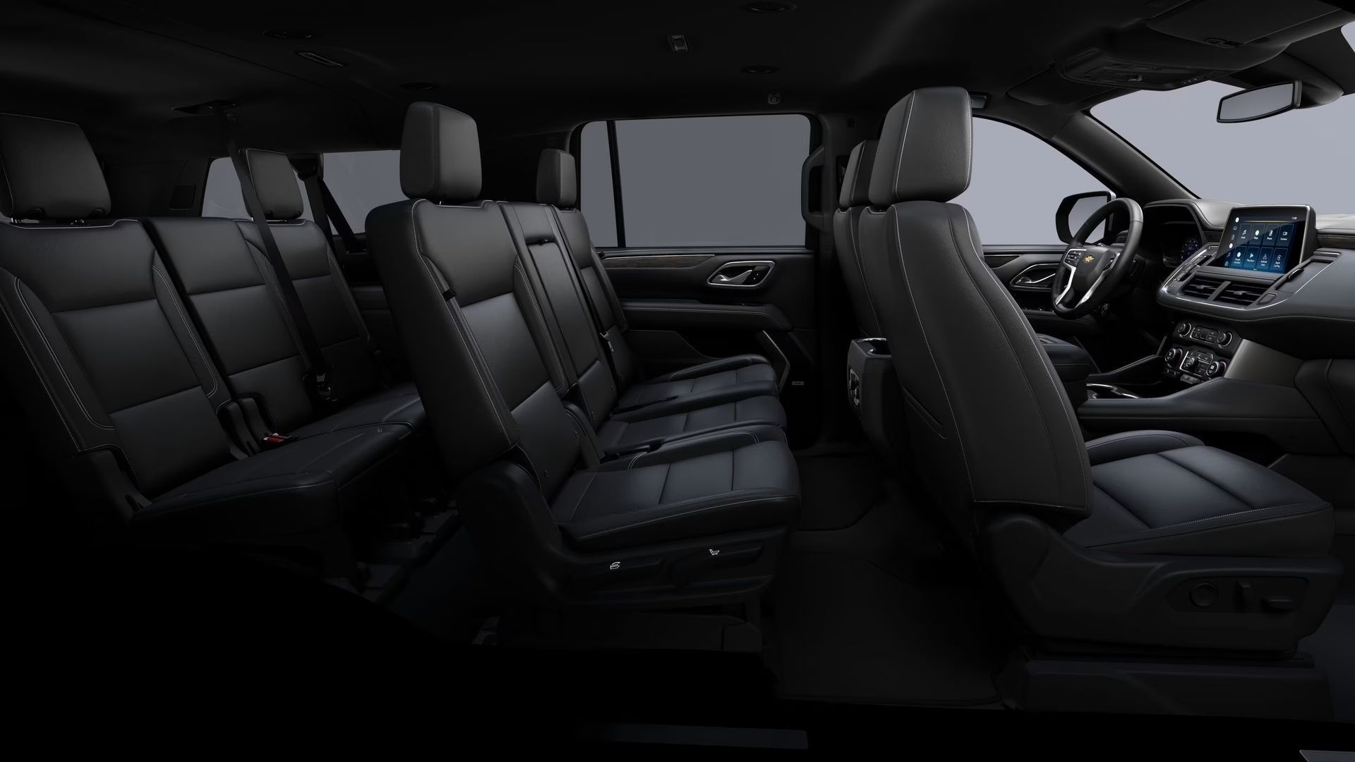 Black interior of a large SUV, showing multiple rows of seats and a dashboard.