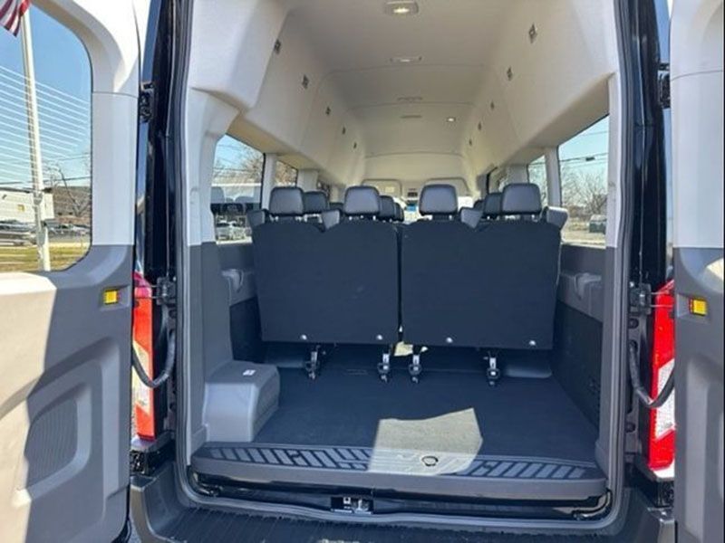 Interior of a black passenger van, showing rows of seats and windows.
