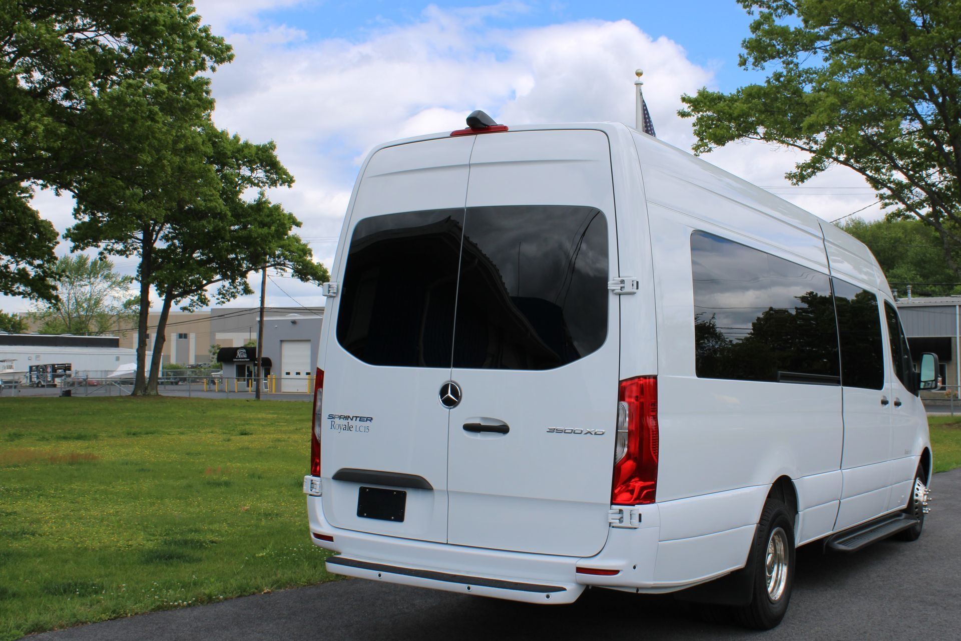 White Mercedes-Benz passenger van parked on asphalt next to grass, outdoors.