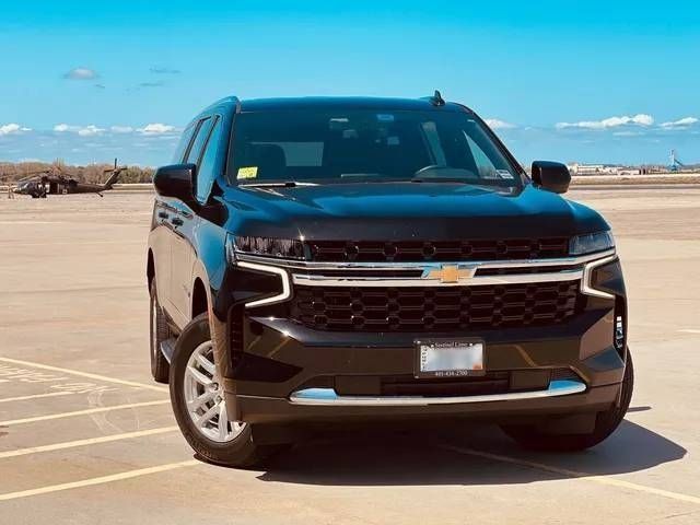 Black Chevrolet SUV parked on an airfield. Blue sky in the background.