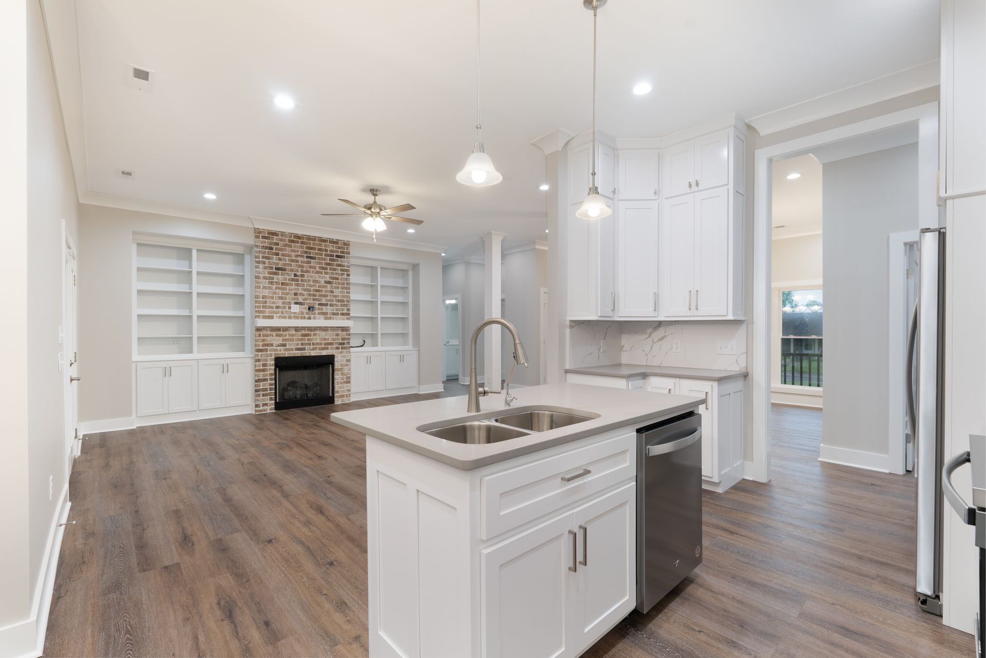 Bright modern kitchen with white cabinets, island sink, stainless appliances, and open view to living room.