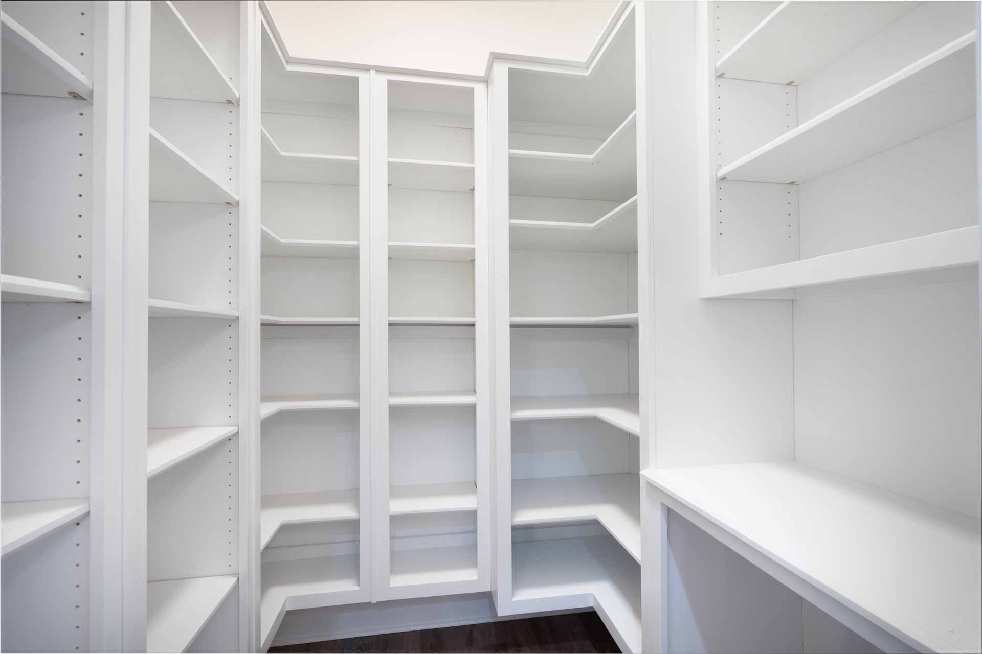 Bright white walk-in closet with built-in shelves and hanging rods, viewed from the doorway