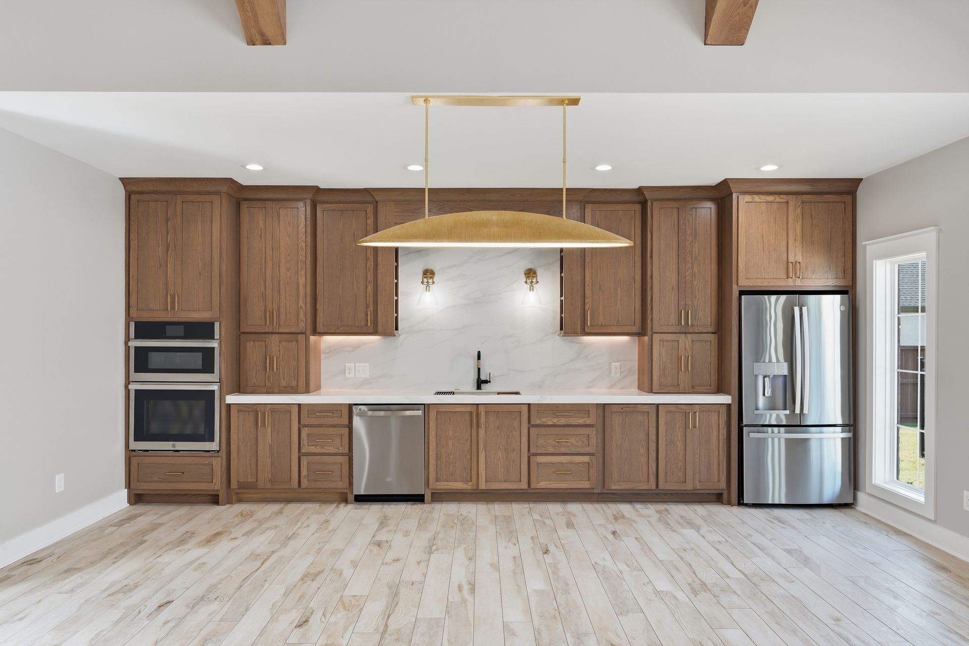 Modern kitchen with wood cabinets, stainless appliances, white countertops, and a large island range hood