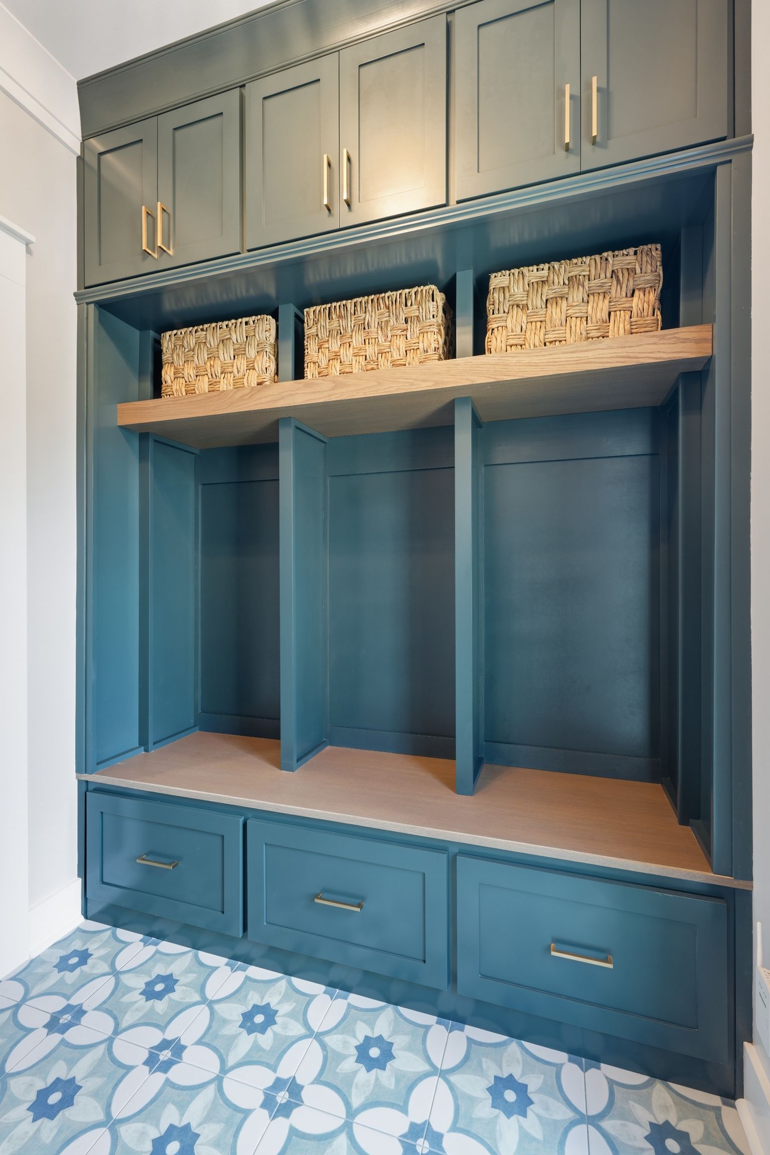 Blue built-in storage cabinet with woven baskets, open shelving, and lower drawers in a bedroom.