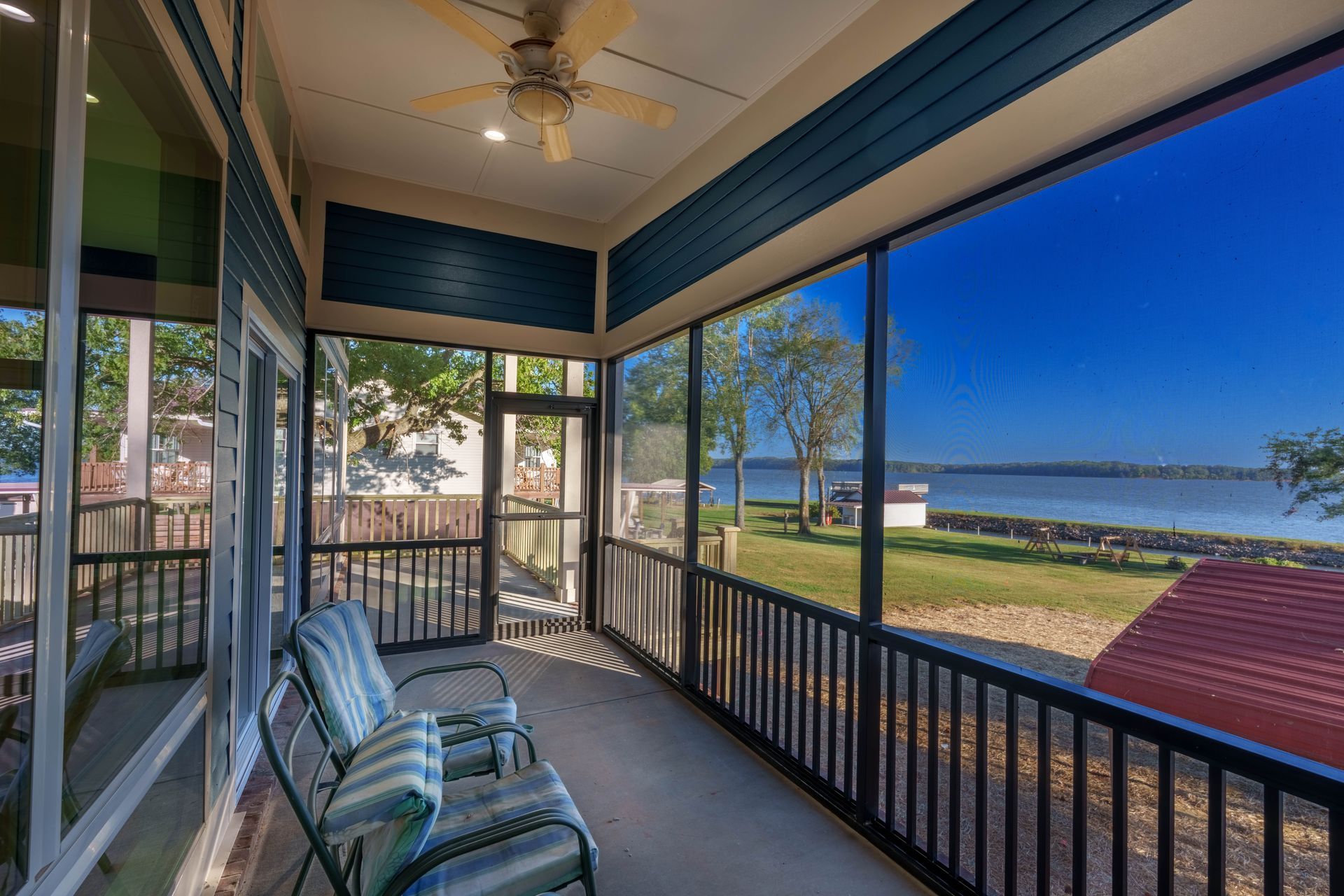 Covered porch with chairs overlooking a waterfront and grassy shoreline at sunset