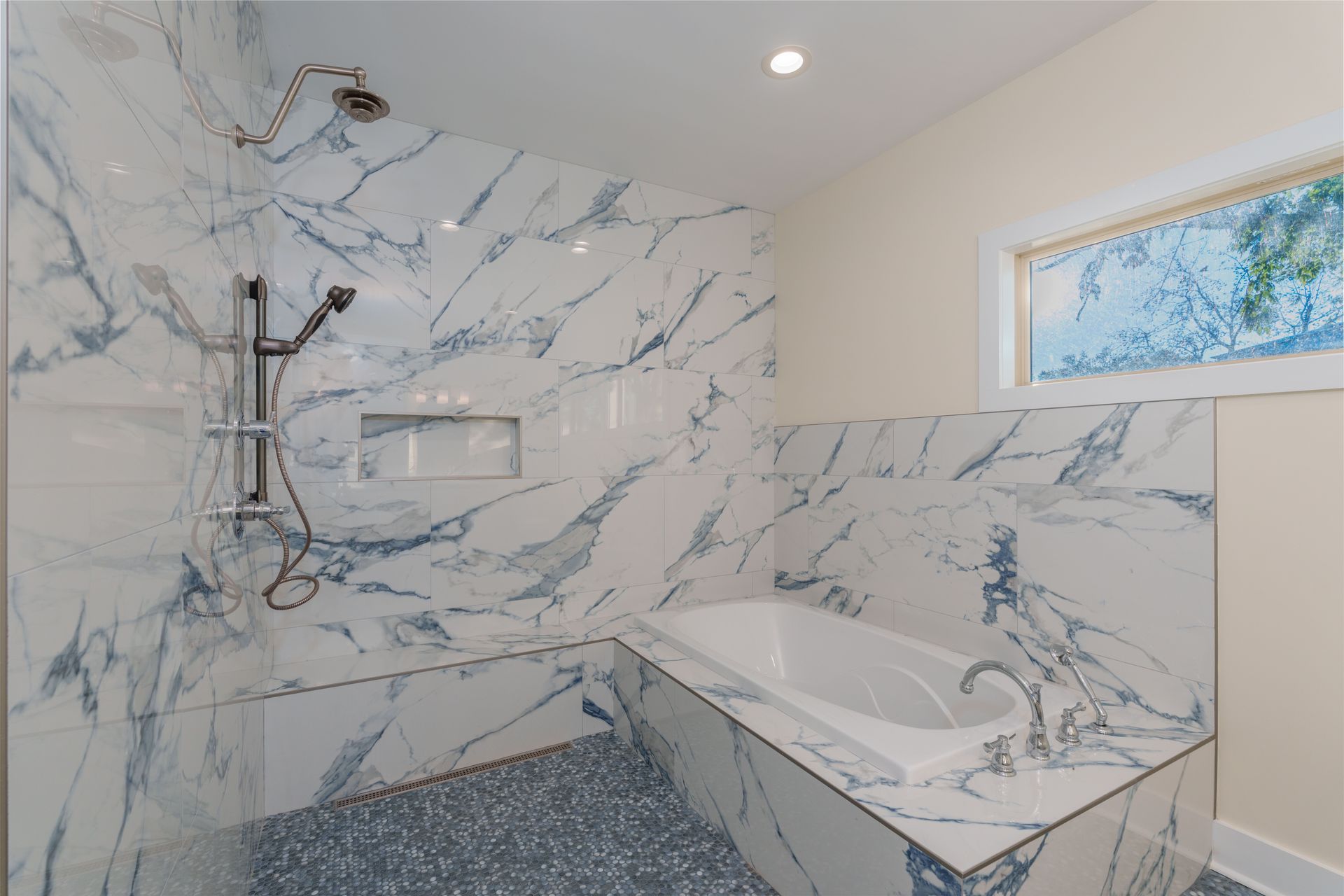 Marble-tiled bathroom with a walk-in shower, built-in tub, and blue-gray veining accents