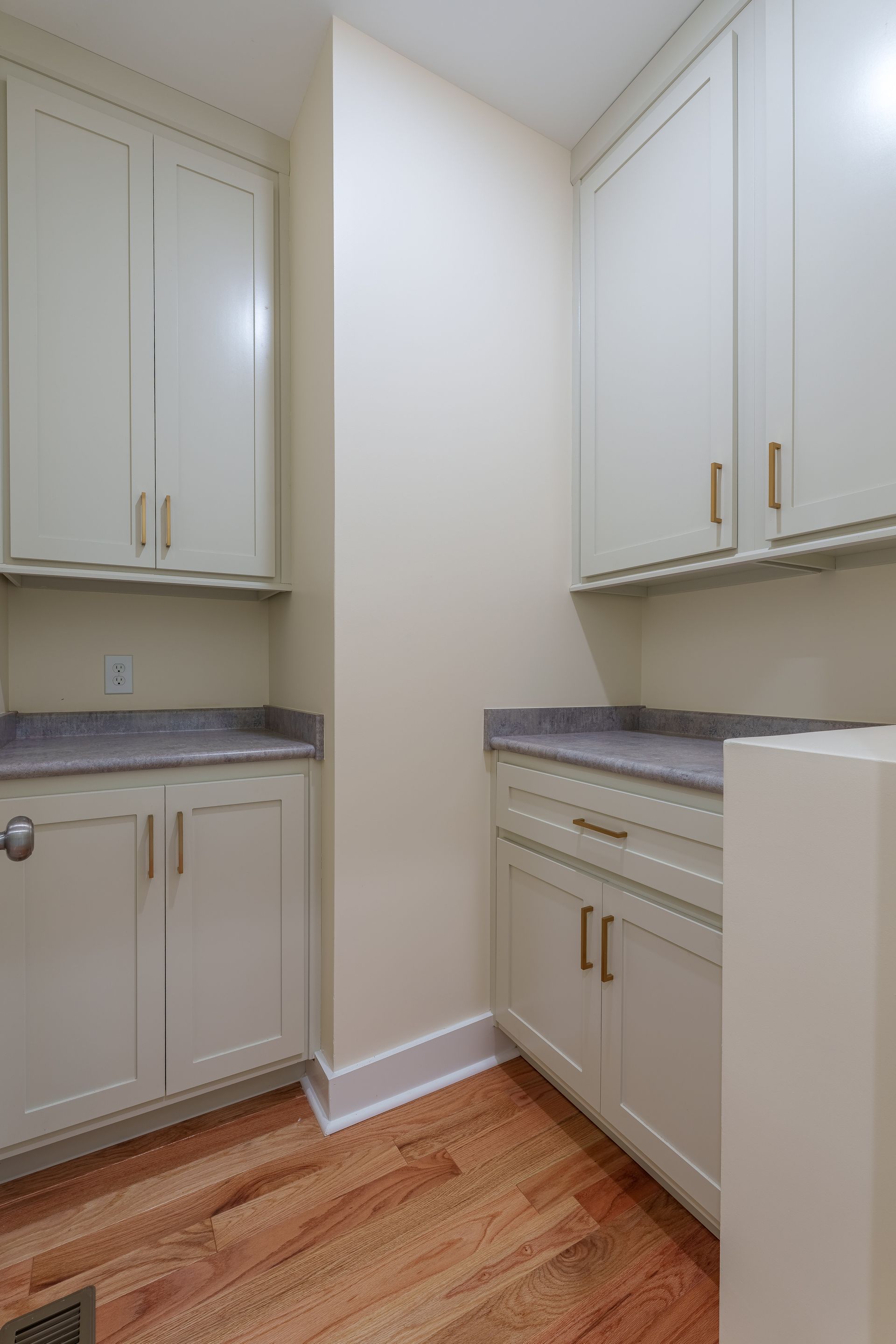 Empty galley-style kitchen with white cabinets, granite countertops, and hardwood floor