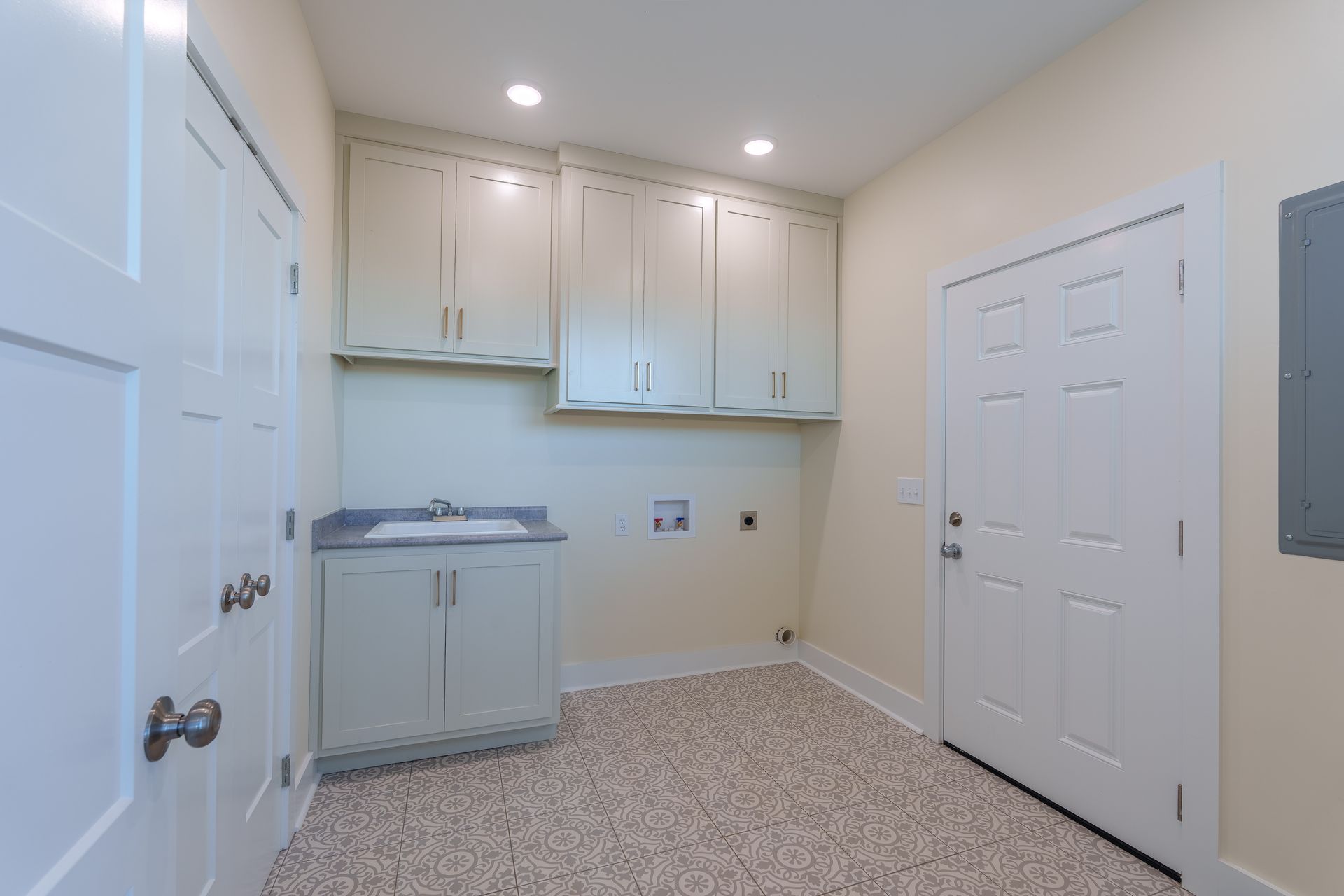 Small utility room with white cabinets, sink, and beige carpeted floor.