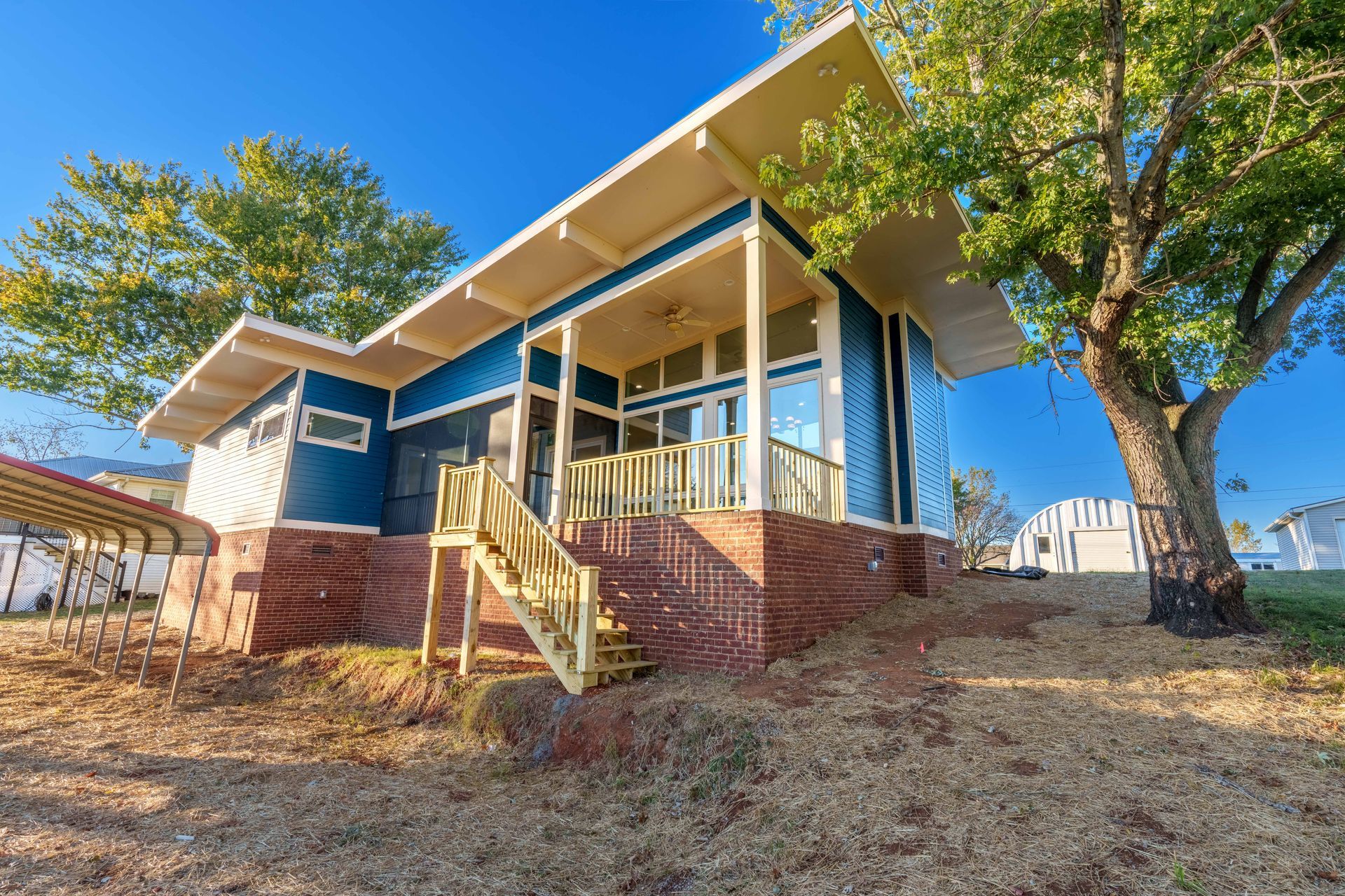 Blue house with front porch, steps, and trees on a sunny day