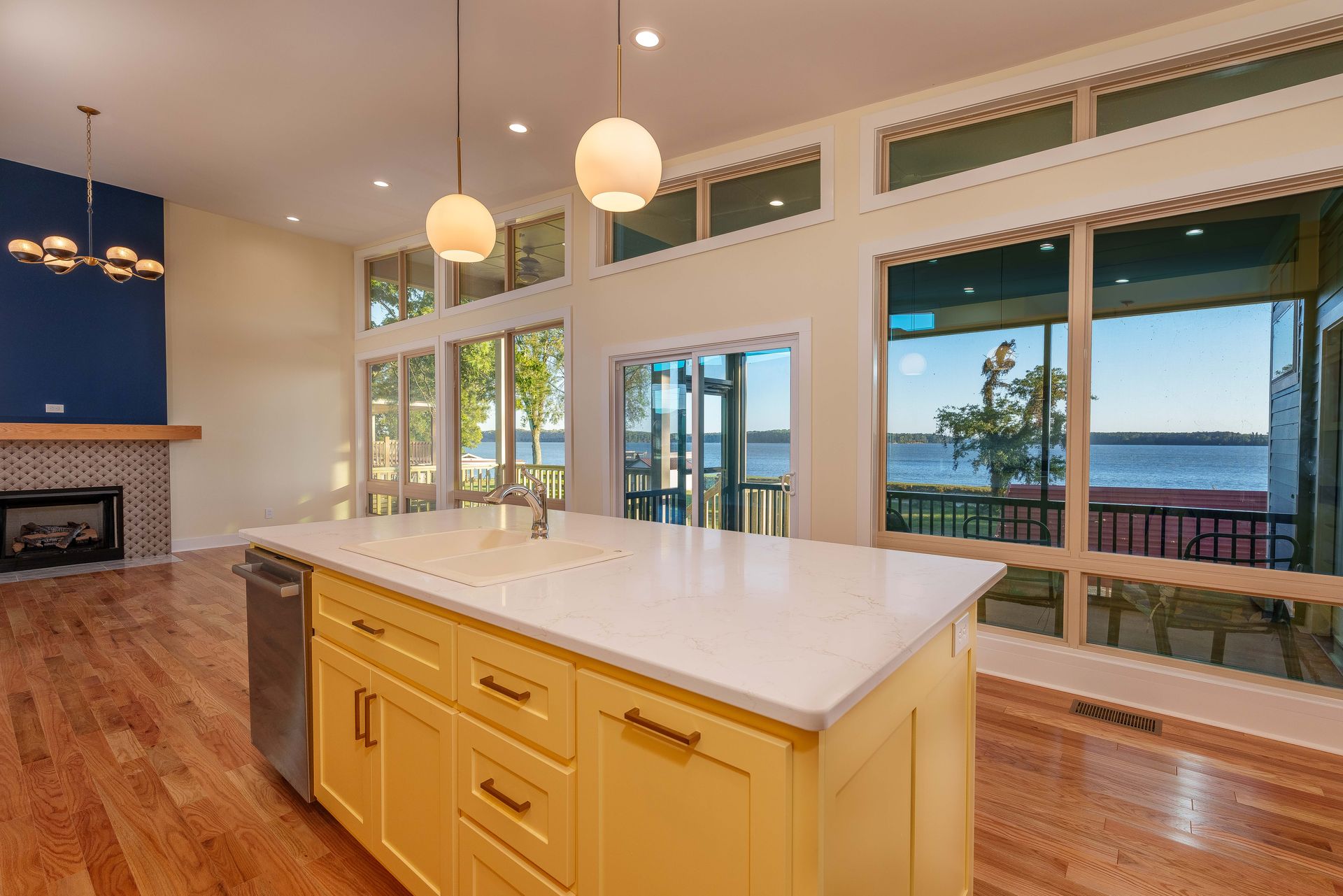Bright kitchen with island, hardwood floors, large windows, and a view of the water.