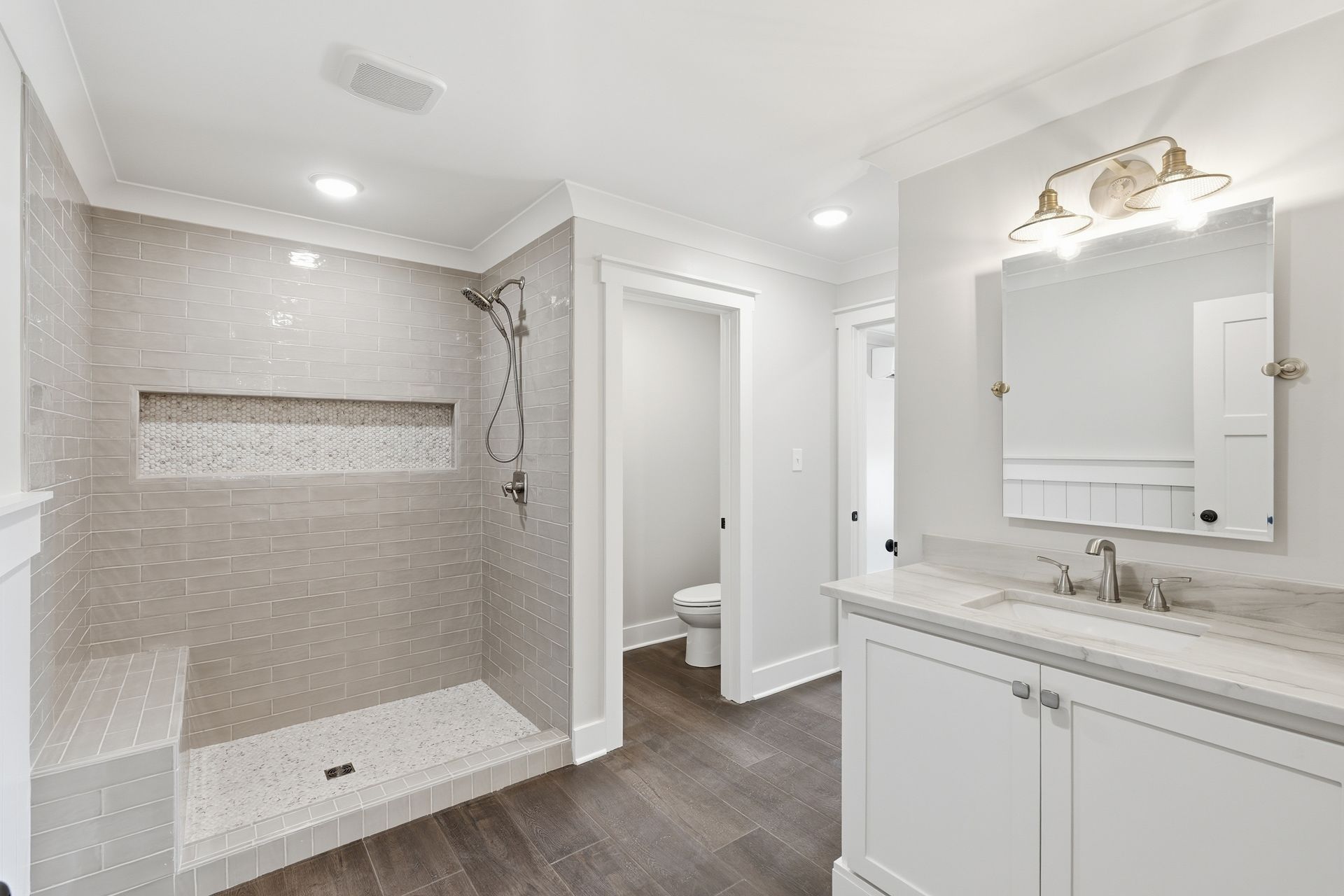 Bright modern bathroom with walk-in shower, white vanity, and gray tile floor