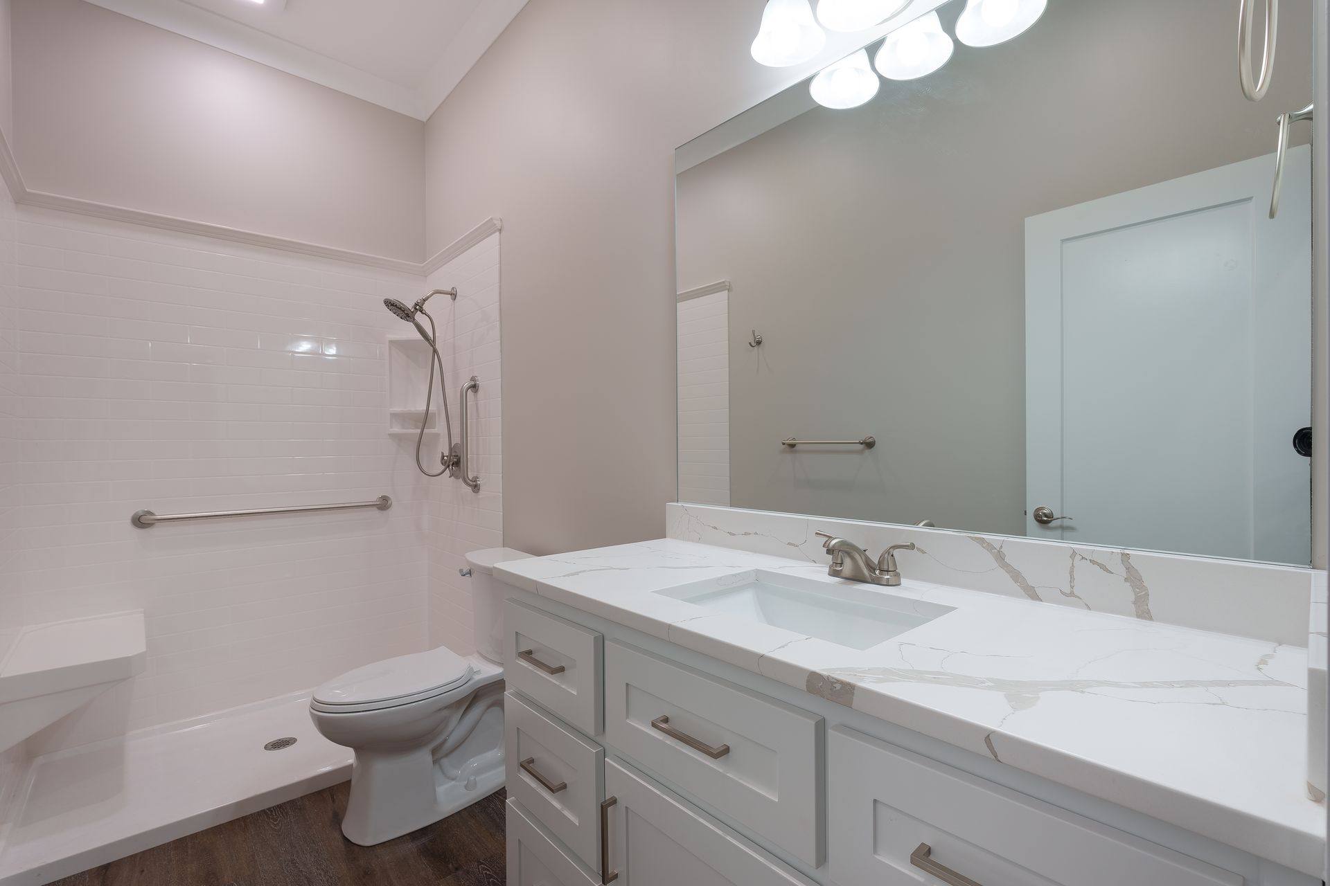 Bright bathroom with double vanity, large mirror, white cabinets, and a tub-shower combo.