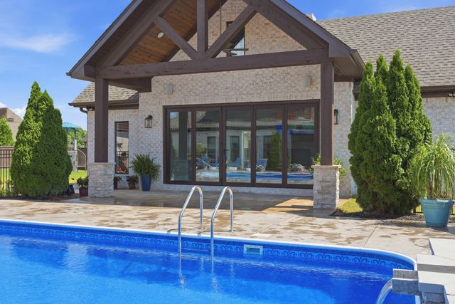 Stone house with a covered patio and large pool in the foreground