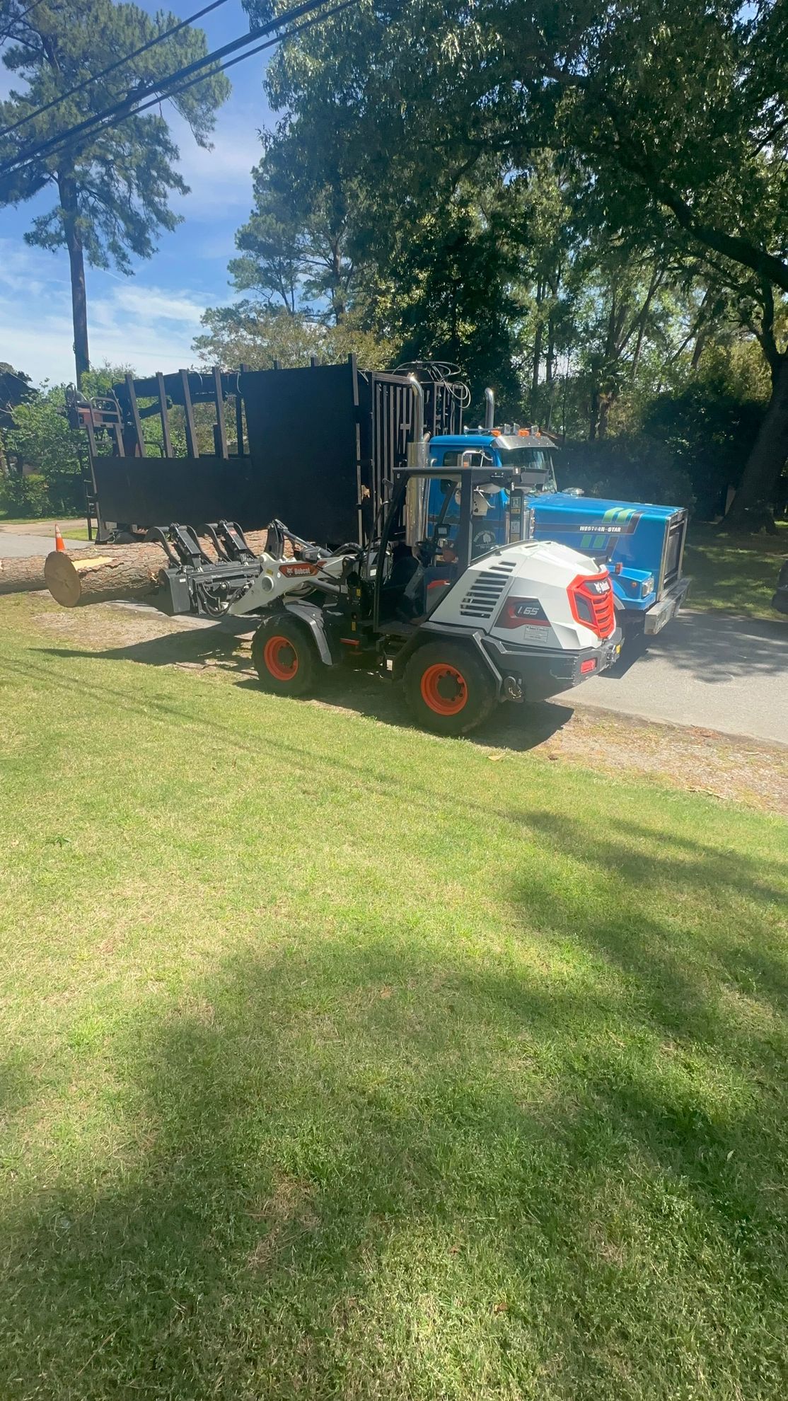 A small white truck carrying a log