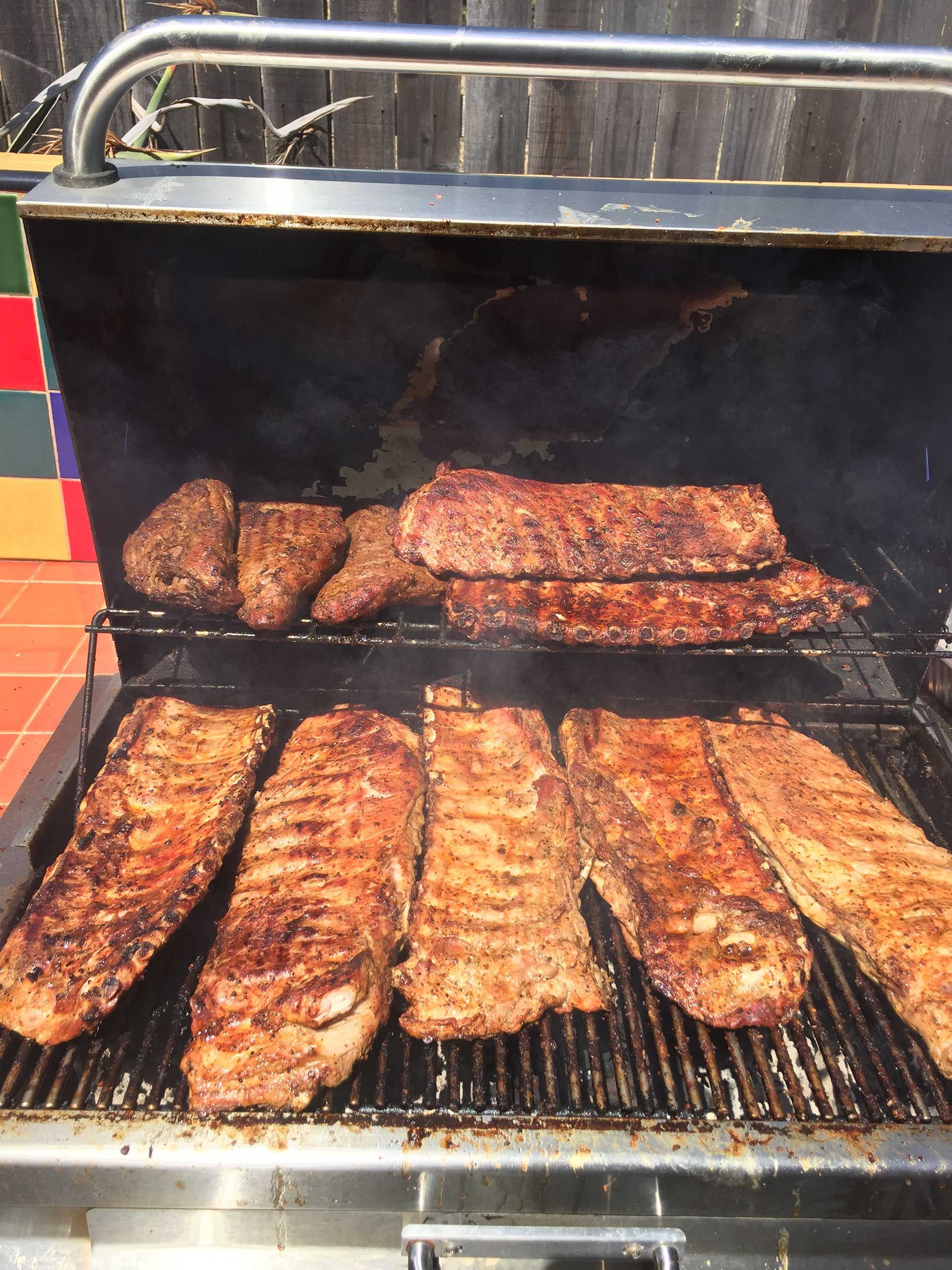 Ribs and other meats are cooking on a grill