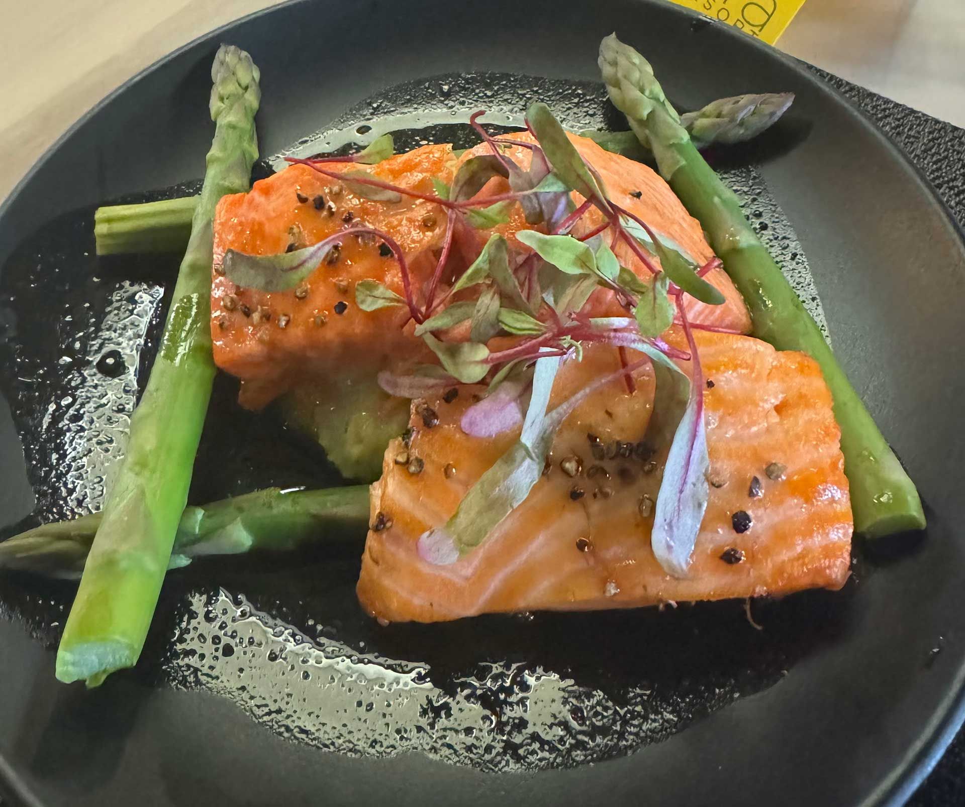 A black plate topped with salmon and asparagus