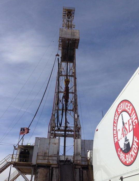 Oil rig with wireline services truck; sunny day.