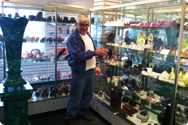 A man in a blue jacket is standing in front of a glass display case in a store