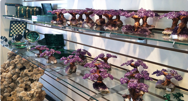 A row of purple trees are sitting on a glass shelf.