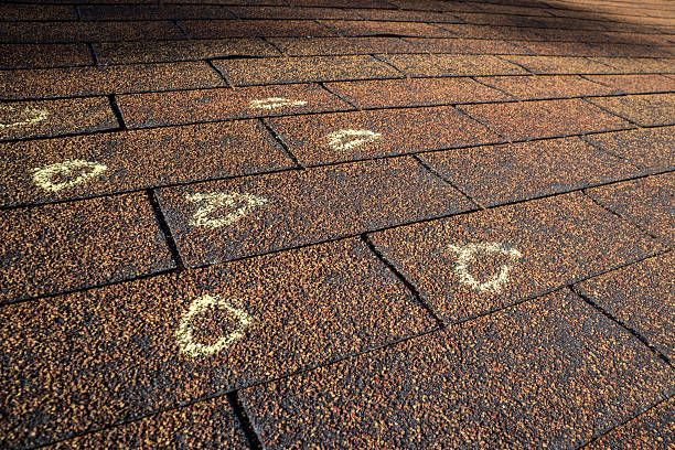 Hail damage marked with chalk on a brown shingled roof.