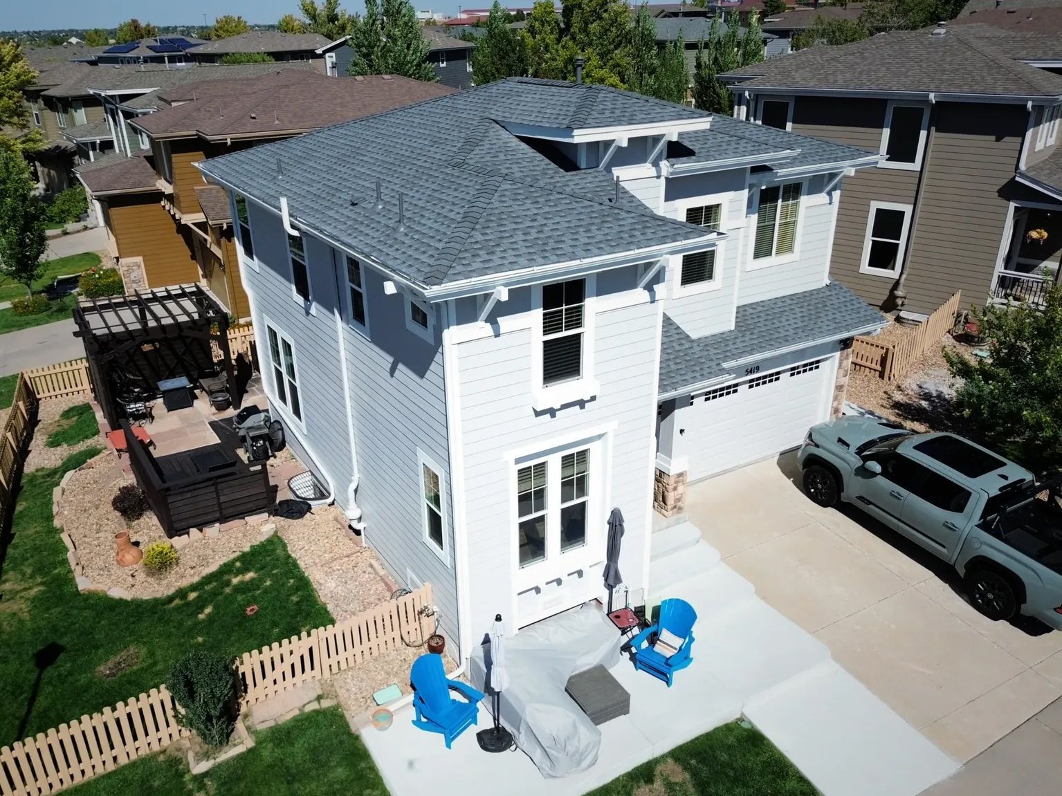 Two-story blue house with a gray roof, a driveway, and a truck parked outside.
