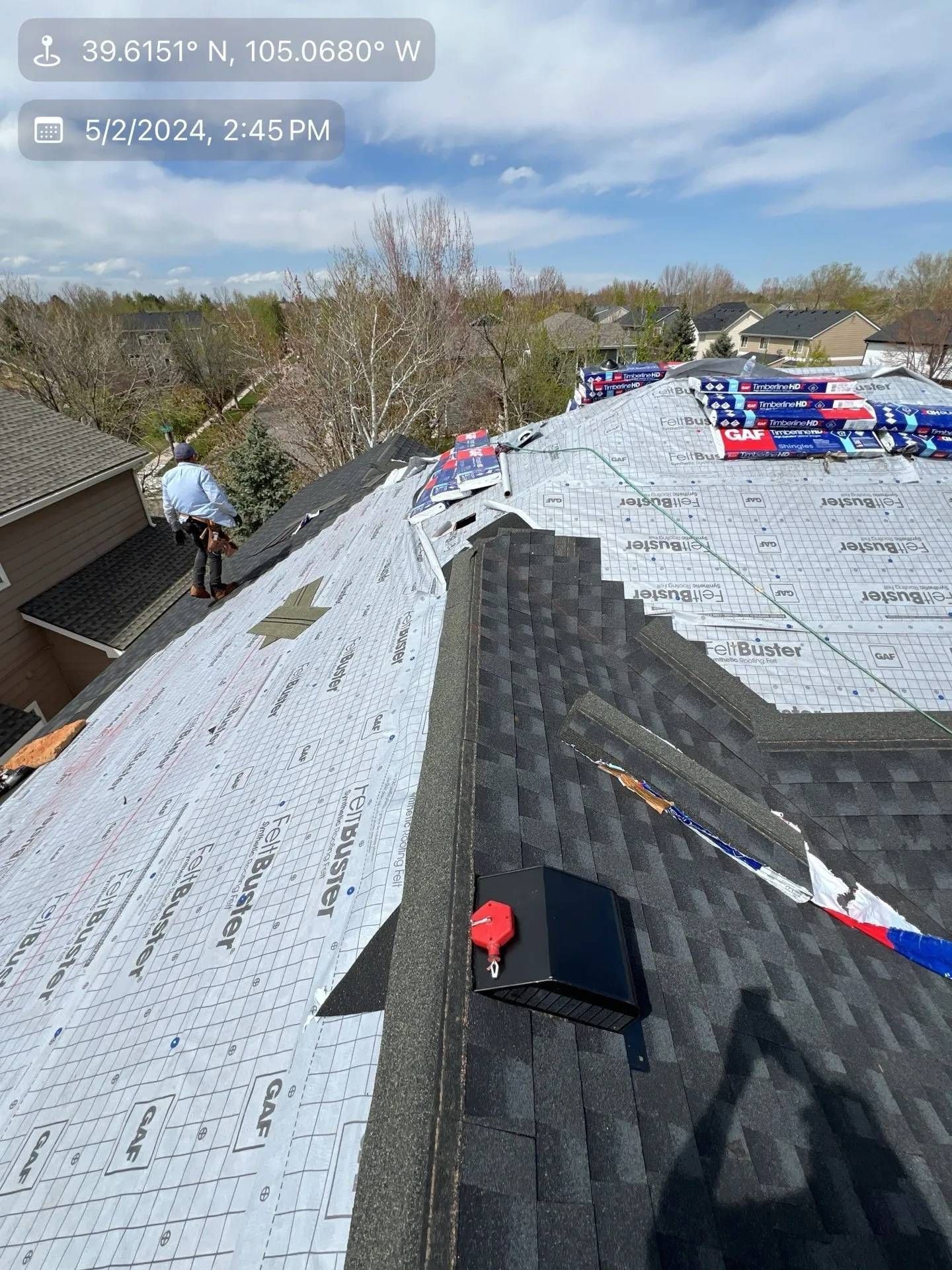 Roofers on a residential roof. Shingles and underlayment visible; blue sky.