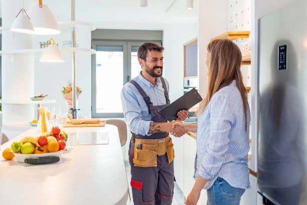 A repair technician shaking hands with a woman in a kitchen with a modern design.