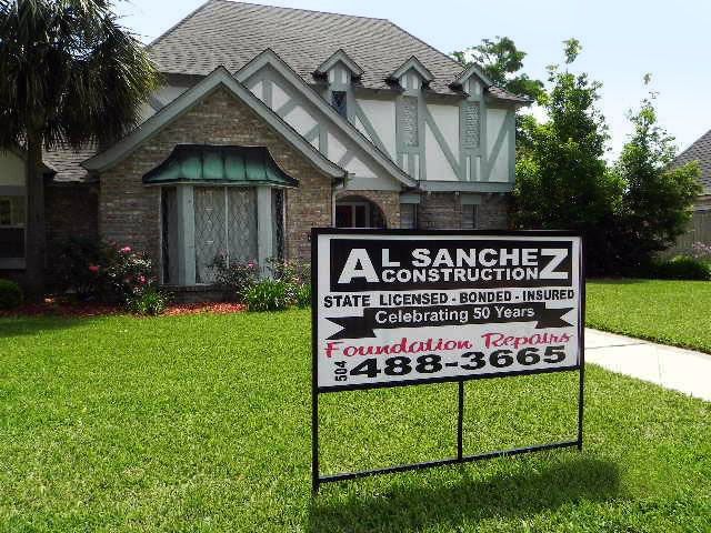 A sign for al sanchez construction is in front of a house.