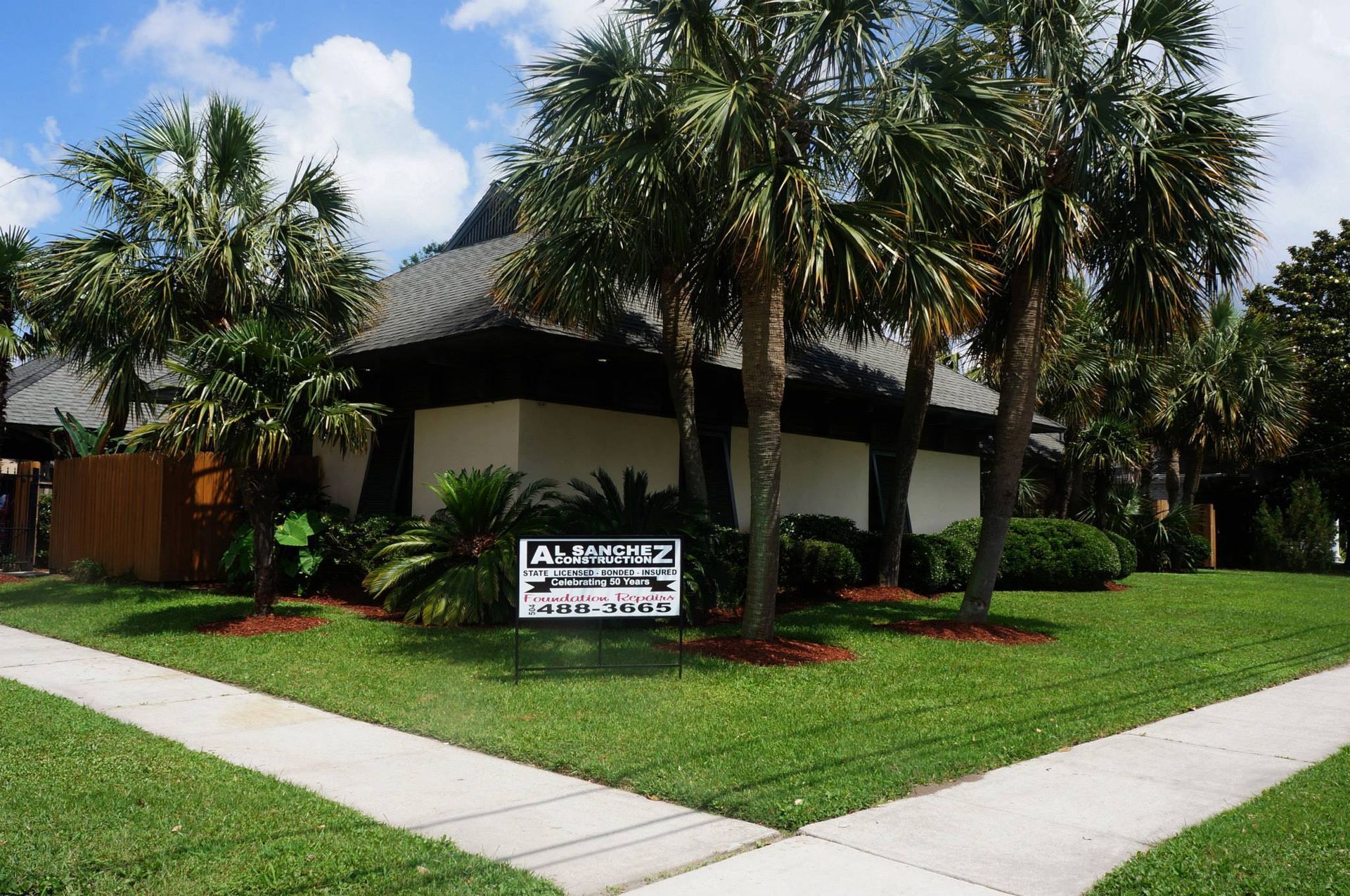 A white house with palm trees in front of it.
