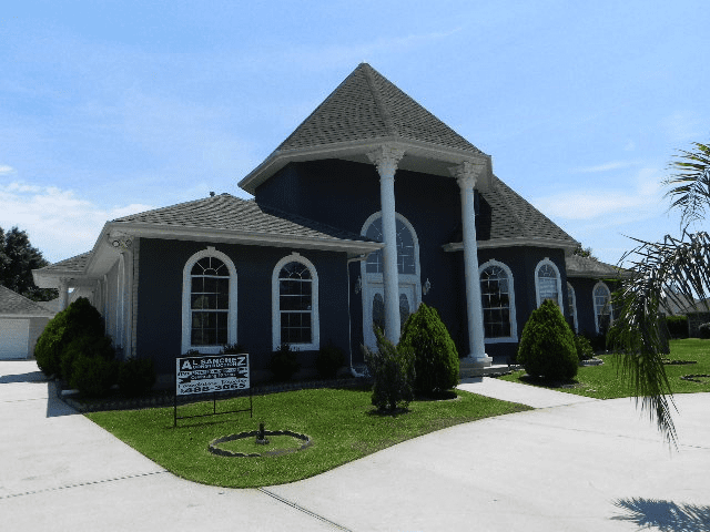A large black house with a sign in front of it.