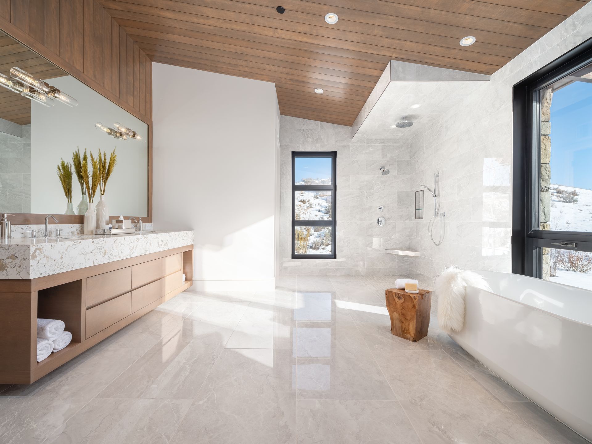 A bathroom with two sinks , a tub , a mirror and a window.