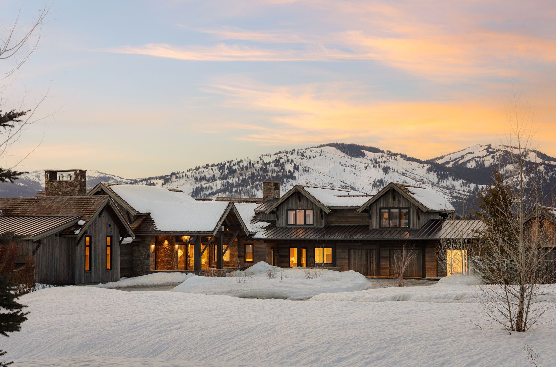 A large house in the snow with mountains in the background