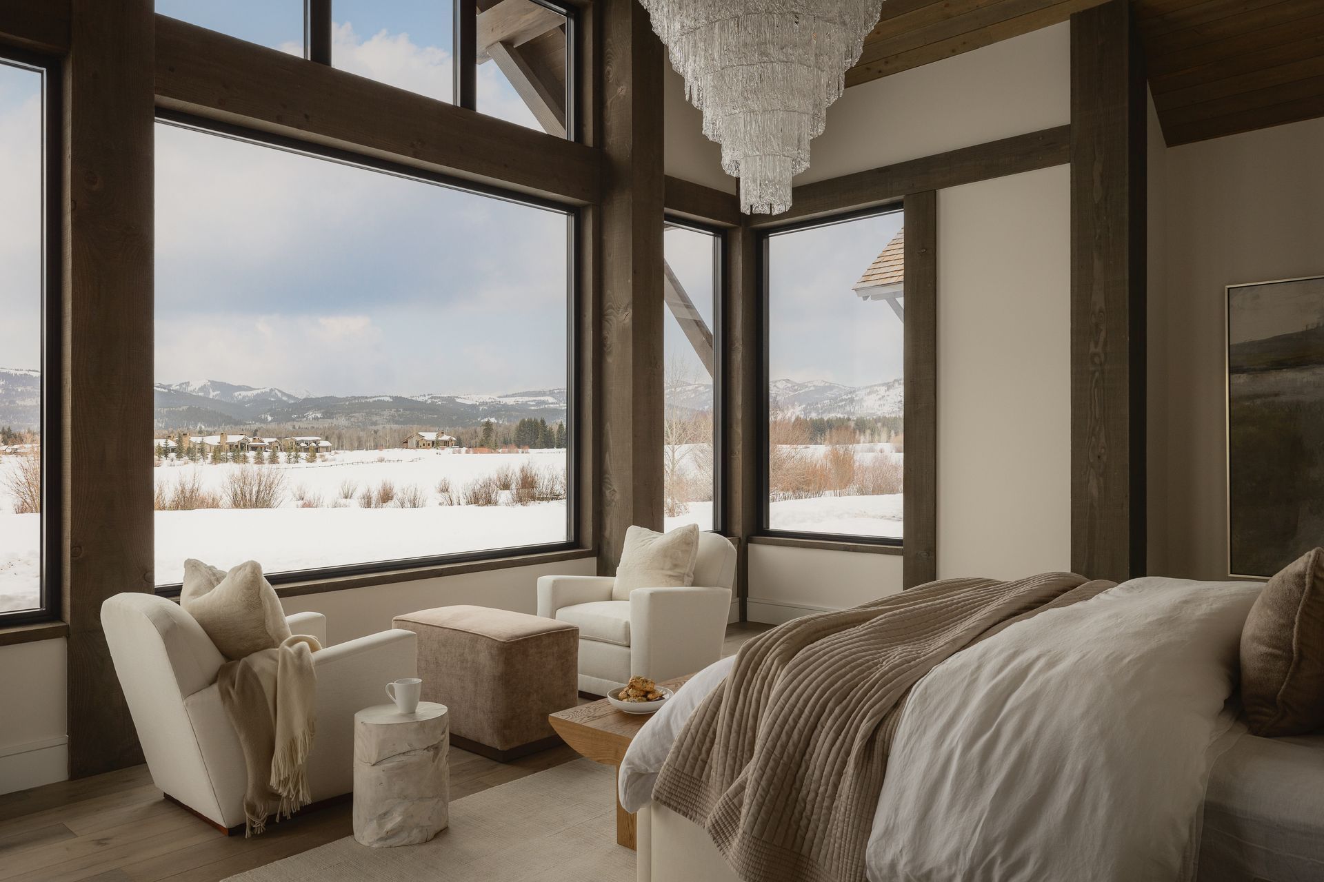 A bedroom with a bed , chairs , and a large window with a view of a snowy field.