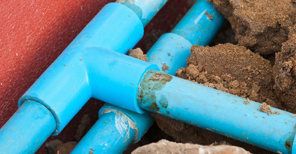 Blue PVC pipes with muddy soil around them in a trench