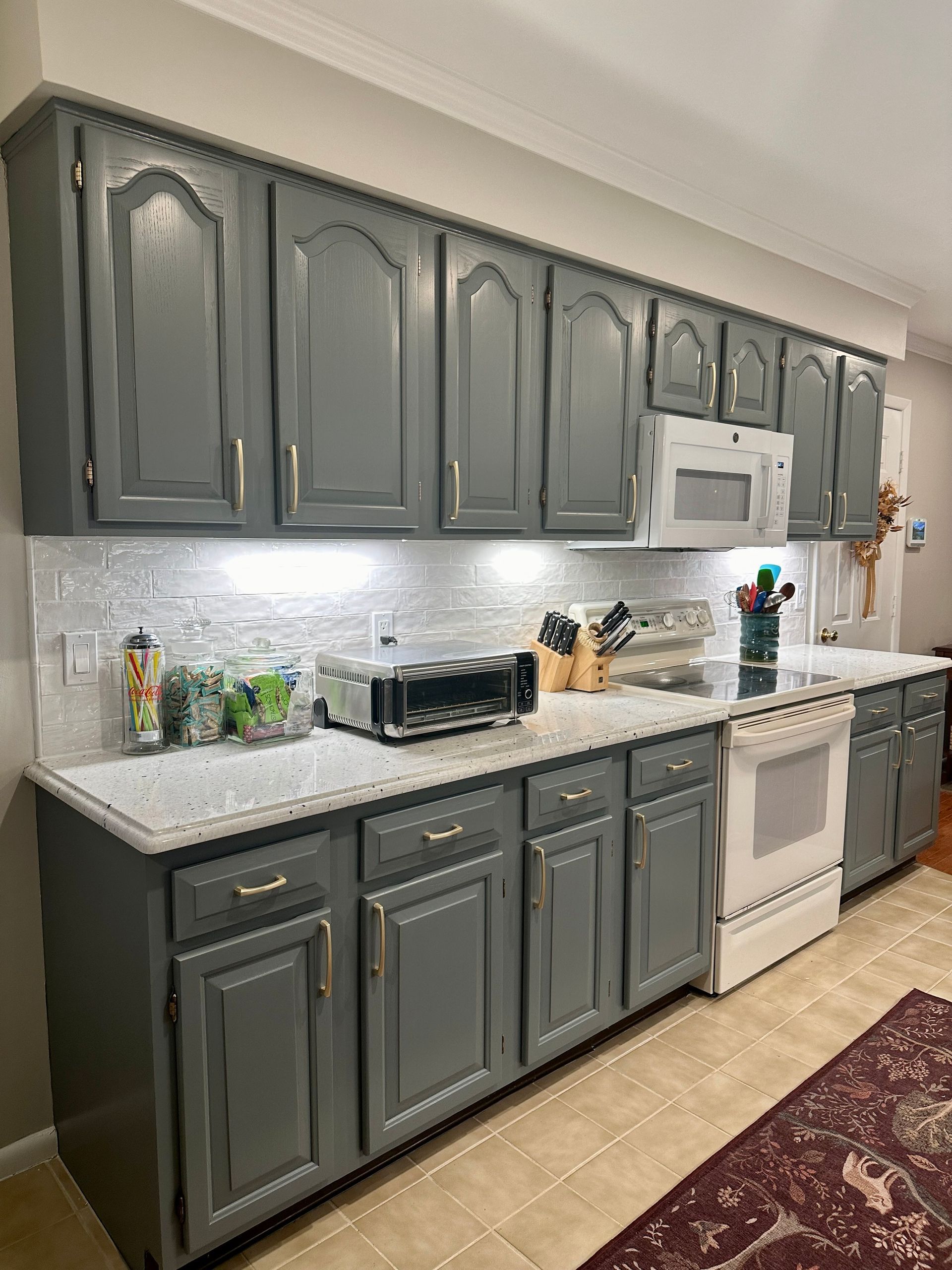 Gray kitchen with white countertops, stainless appliances, and light wood tile flooring