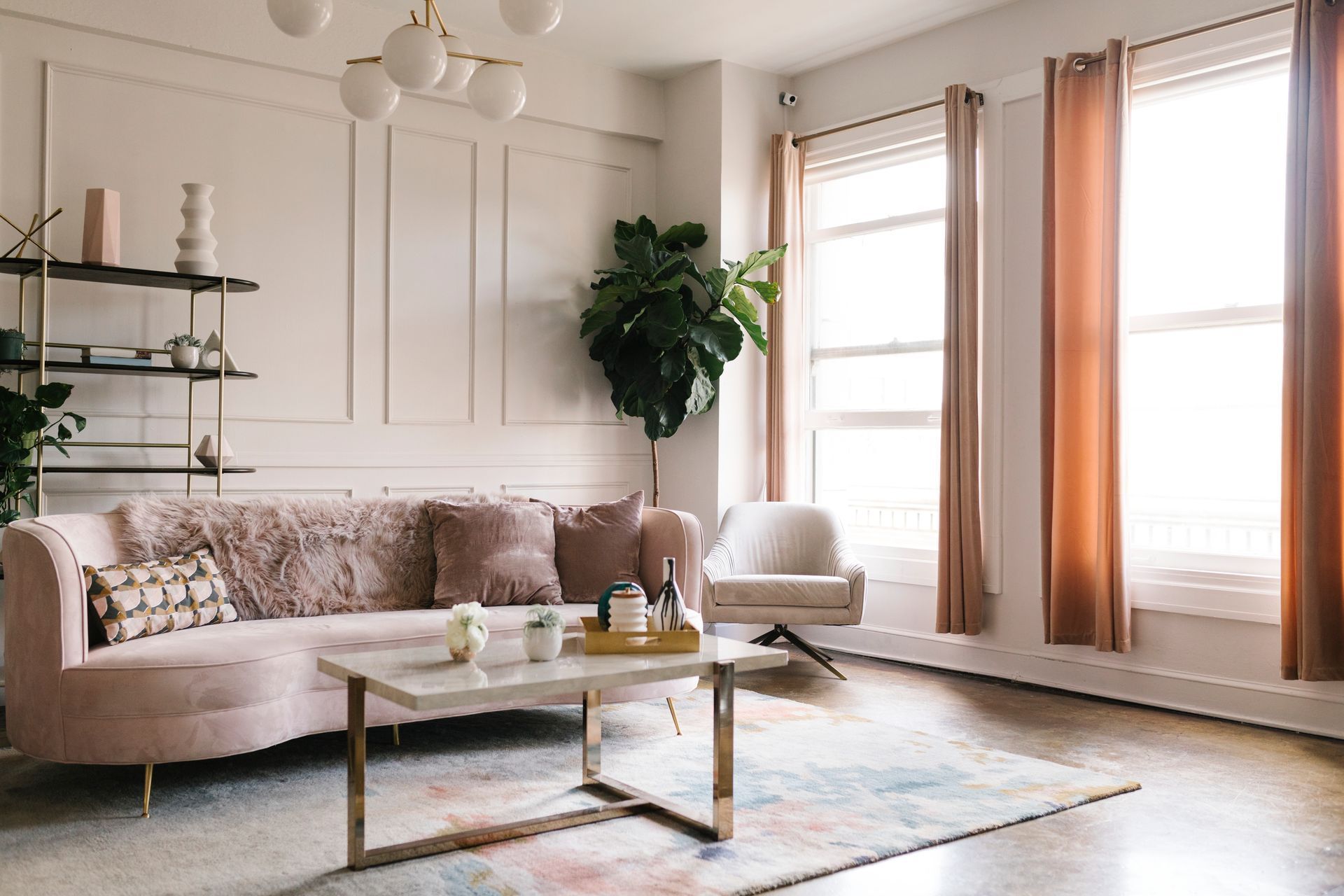 Bright modern living room with beige sofa, coffee table, plants, and large windows with curtains