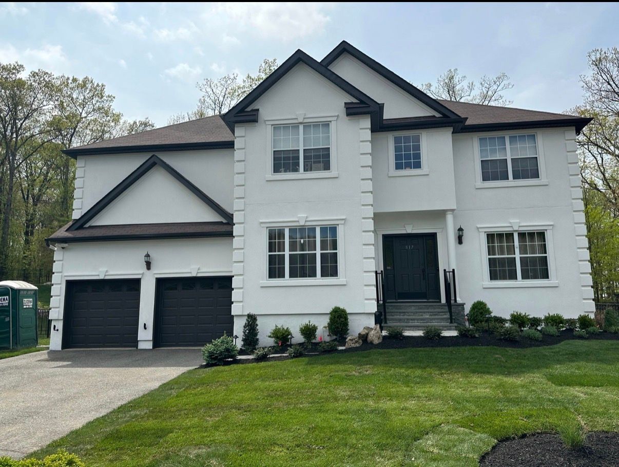 White two-story suburban house with a double garage, front lawn, and stone-trimmed entry