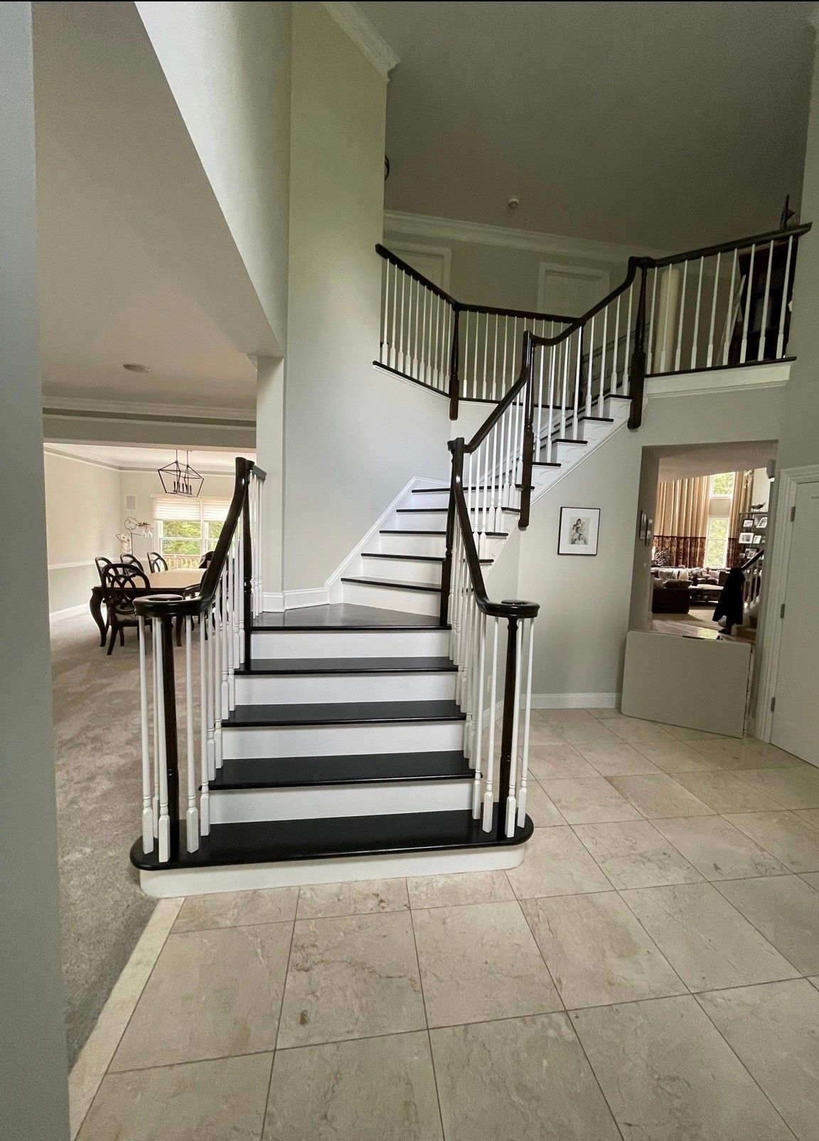 Staircase with black-and-white runner in a beige home, leading to an upper landing and hallway.