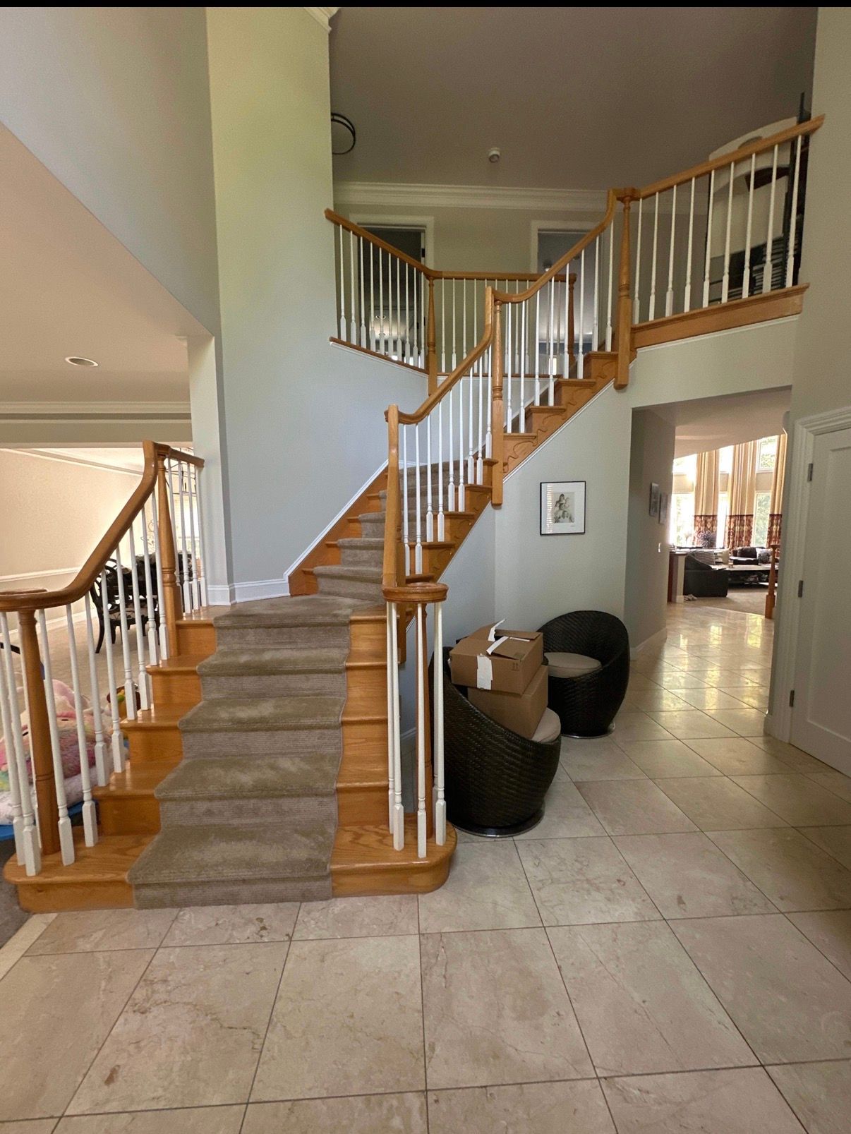 Two-story foyer with carpeted staircase, white tile floor, and wooden banisters leading to upper hall.