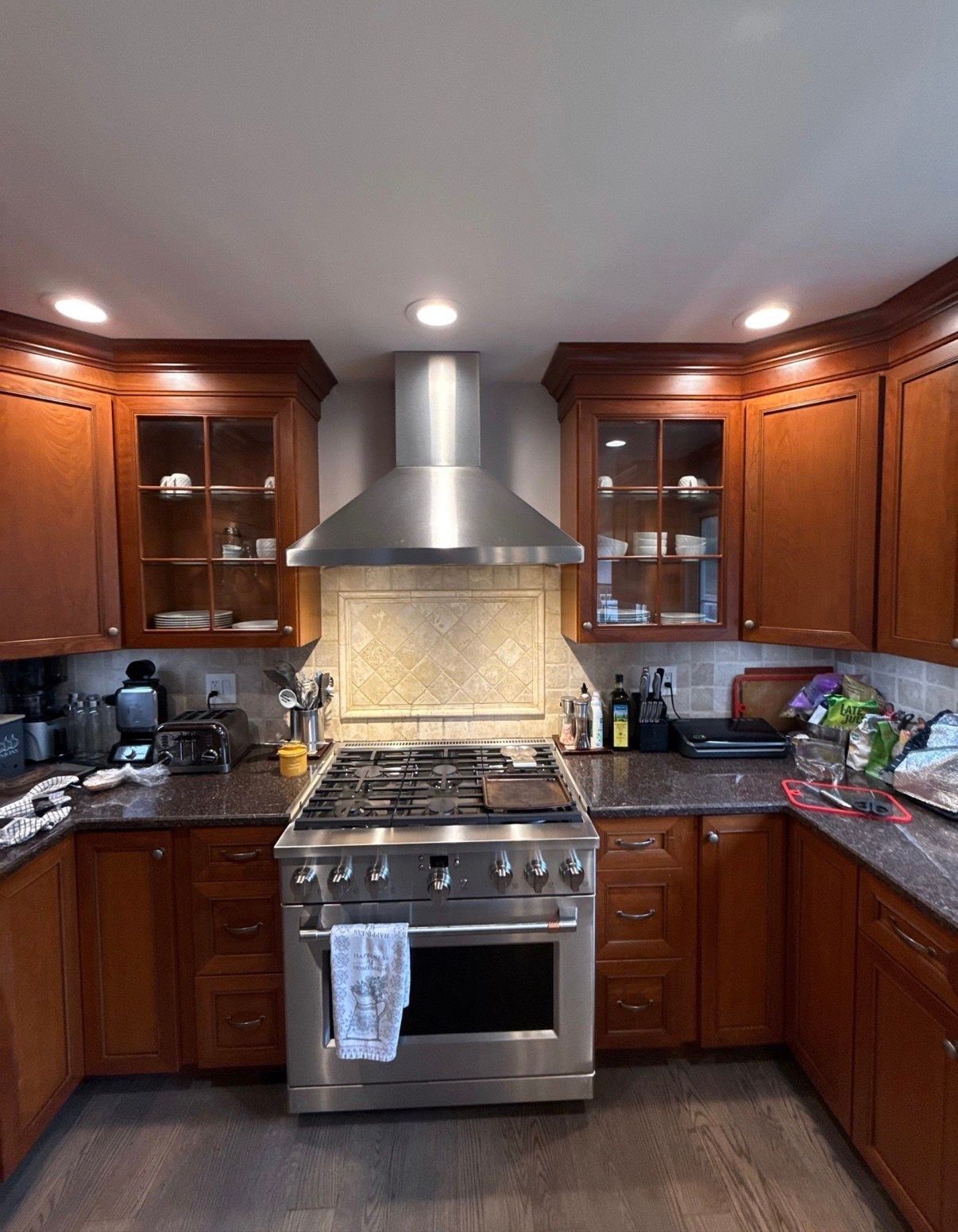 Modern kitchen with dark wood cabinets, stainless steel stove and hood, and granite countertops